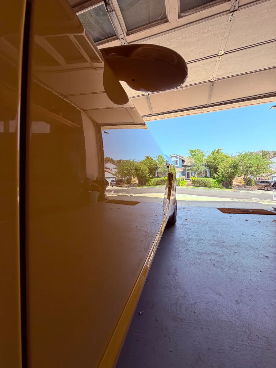 Freshly detailed car reflecting the street outside an open garage door